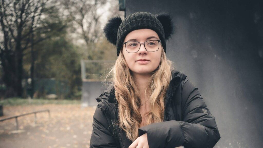 En ung jente sitter på i en park om høsten.
